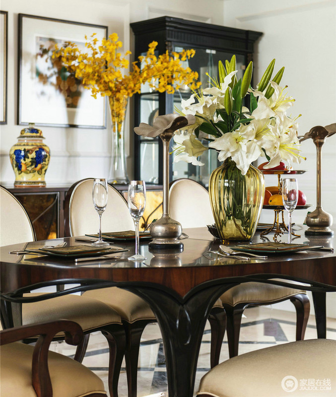 棕色木餐桌散发着釉亮，彰显出不一般的品质；玻璃烧制的淡黄色花瓶因百合花的陪衬越发精美，餐桌也应打造一番才让家更温馨。