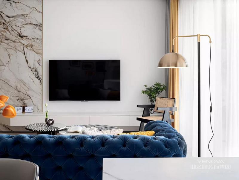  客厅围绕深蓝色沙发奠定复古优雅的基调，地毯、茶几上简约流畅的线条，让空间富有灵动的魅力。
