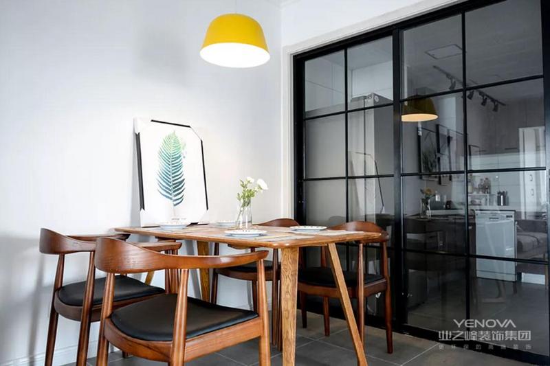 原木风的餐桌椅搭配黑色的坐垫，餐桌上摆放了干花和绿植装饰画作为点缀，黄色的吊灯让餐厅更显活力