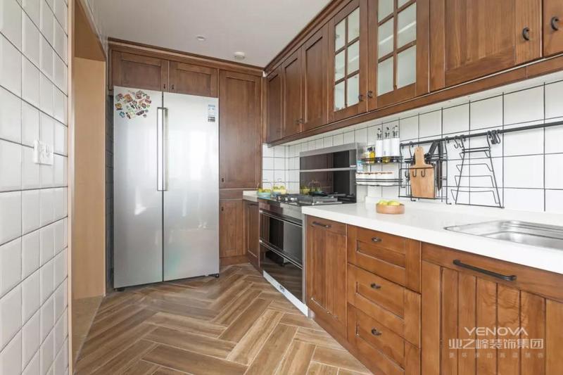 厨房内部做了U型的橱柜布局，冰箱也被嵌入柜子当中，地面人字铺贴的木纹砖和木质的橱柜相互呼应，显得整个厨房都很有自然感