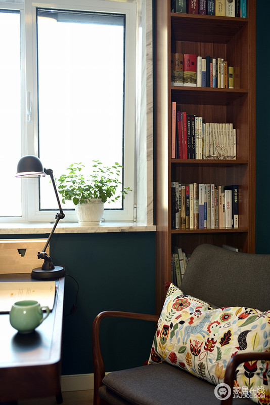 书房沉稳的墨绿色墙面，镌刻着自然幽深；实木书柜和书桌等家具十分实用，简洁的造型并没有累赘感，北欧折叠台灯和花色靠垫表达出主人对生活品质的不凡追求，让人可以安心休憩阅读。