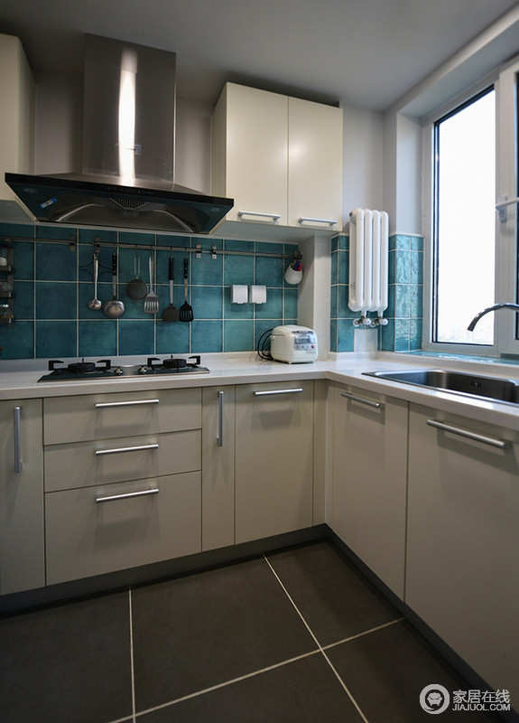 厨房空间不大，但是设计师利用白色橱柜来增加储物等实用功能，并借蓝色墙砖与之构成色彩应和，让空间不缺乏艺术感；灰色地砖易于打理，与整体空间十分和谐，实用与美观并不矛盾。