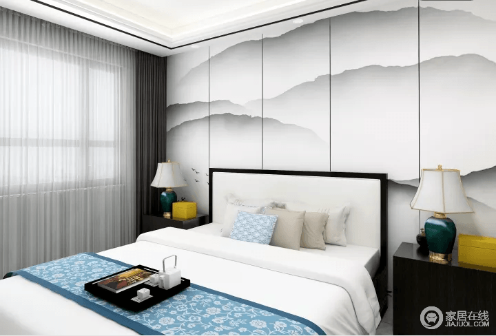 卧室的背景墙以一副水墨画似的画作来营造中国山水的静怡灵动，实木长头柜和绿色陶瓷台灯对称之中，彰显了恬静淡雅；蓝色薄毯带来轻和，俞显温馨。