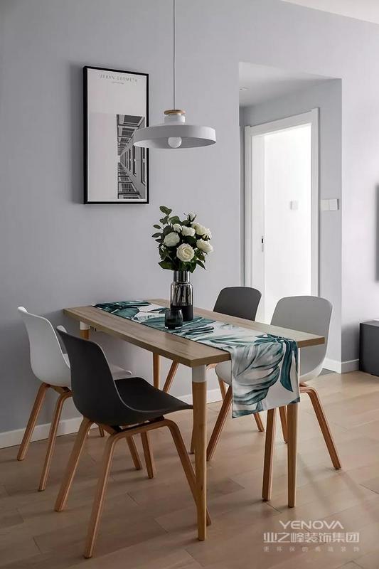 简洁的木质餐桌，搭配灰白配的餐椅，在灰色墙面空间搭配下，挂上一幅简约自然的装饰画，还有一盏独特文艺的吊灯，带来的是一个舒适轻松的用餐氛围。
