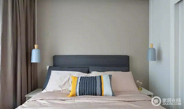 卧室线条整洁，米色壁纸让背景墙简单朴素，与深驼色窗帘呈色彩对比，蓝色木质吊灯清雅灵动，与驼粉色床品搭配出柔和，而黑灰色及条纹靠垫带着优雅，让生活格外舒适。