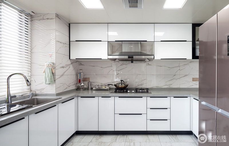 厨房以白色灰纹墙砖铺贴出天然的肌理之美，在硬朗之余，给空间带来柔和感；白色橱柜上下巧妙地定制在空间，规避了空间结构的缺陷，十分实用，浅灰色水磨石台面调剂出素雅，令空间格外简洁。