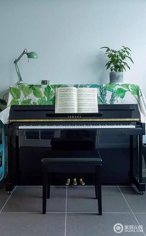 黑色钢琴上铺有带有绿色植物图案的桌布，好看得很！
