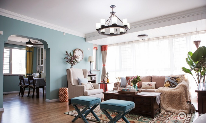 客厅以蓝色和白色为主，渲染了一个足够清新的空间，花式门框墙体增加了空间的地中海风情，颇为精致；美式布艺沙发以米色和蓝色组合的方式，增添了生活的温馨和轻奢。