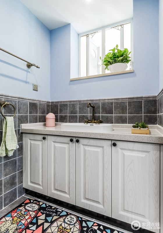 卫生间的墙面以淡蓝色和灰色瓷砖为拼接设计，既实现美学设计，又能让墙面保持防水性；盥洗柜木灰色的设计略显朴质，足显实用利落。