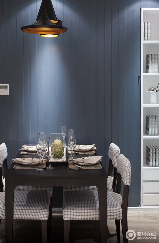 设计师利用墨蓝色将餐桌衬托得尤为时尚，并与白色书柜照应出色彩对比产生的不同效果；白色书柜的收纳功能既不影响空间感，又最大的利用了空间。