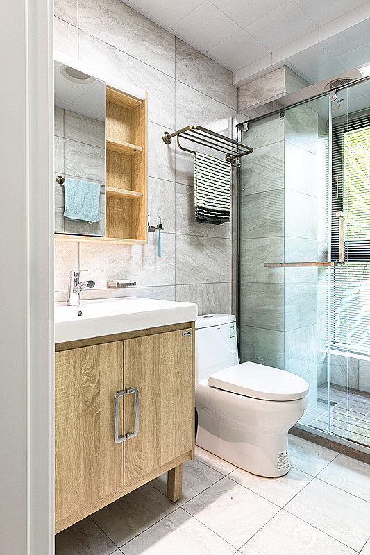 卫生间虽然有承重墙，但是通过灰色哑光砖来作美化，营造出自然淳朴；简洁通透的淋浴房让空间不影响采光，而木质台盆柜也赋予生活北欧特有的味道。