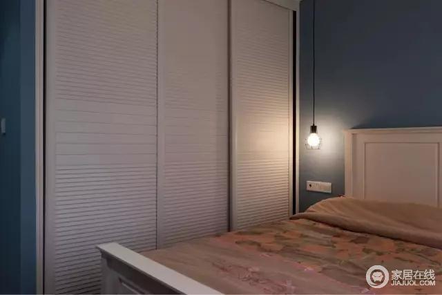  蓝色墙面搭配白色衣柜及床，吊灯是垂坠式的，整个卧室简洁温馨又不失舒适感！
