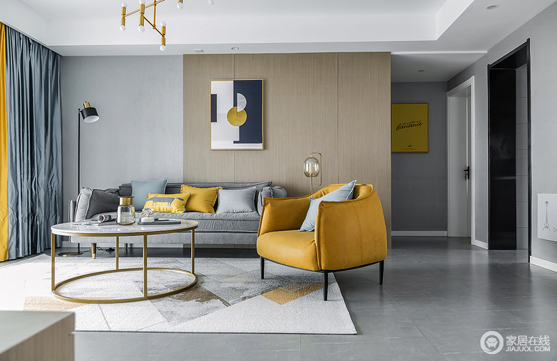 客厅空间整体以灰色为主，大面积的渲染，增添了空间高级感，浅灰色的墙面、地面让空间视感高度统一，跳跃的姜黄色布艺以及单人沙发椅在整个空间中尤为突出，成为整个空间的色彩中心。同时，现代家居非常重视材料的质感，简单中透着一种高级家居的味道，素静中多了摩登。