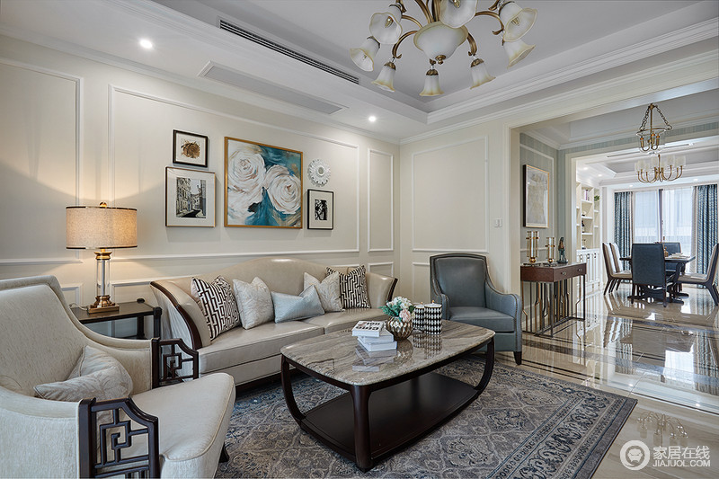 米白色的漆面因为画作而多了一抹色彩感，中性色沙发和藏蓝色皮质扶手椅给予空间和雅；布局有序、精致地家具让空间整个客厅色彩和静而文雅。