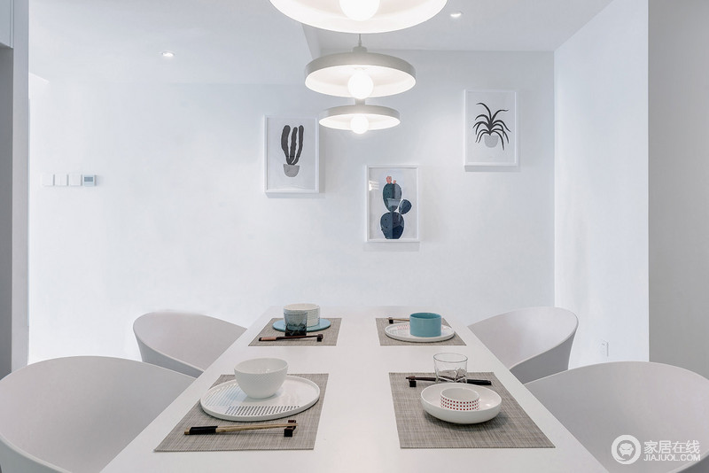 白色的餐厅以实用为主，与厨房一体式设计，增加了利用率；墙上仙人掌等绿植以自然之调，与白色北欧餐椅、简约餐盘等形成简约大气；并排的白色吊灯与蓝色餐具渲染出清雅。