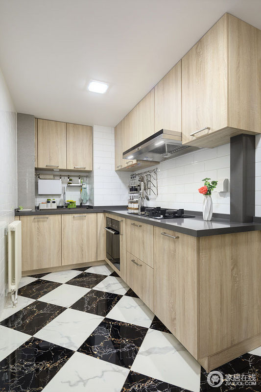 L形布置的厨房，操作很方便;黑白色系的地板、白色墙砖和黑色台面与木色橱柜搭配，营造出简洁又清新的厨房。