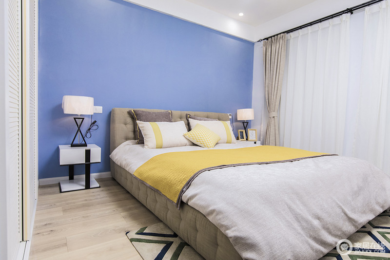 卧室的背景墙以高明度的蓝色刷漆与明黄色被套的强烈对比，使空间的色彩层次愈加丰富活跃，个性地床头柜和台灯组合让整个卧室在温馨多了不少趣味。