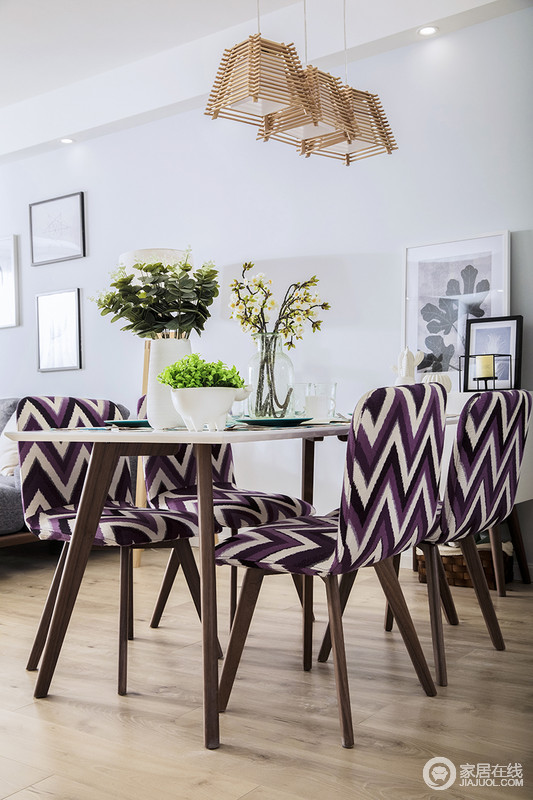 餐厅紫色的花纹椅给整个空间增添了几分活力与时尚，原本开放式的餐厅更有格调；实木地板带来北欧的轻暖，餐桌上的花器和旁侧挂画组合，点缀出生活的小惬意。