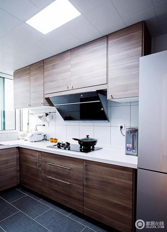 厨房里黑胡桃木色的橱柜与深灰色地砖搭和白色墙砖，制作出层次感，营造出沉稳大方的气质，也让整个厨房显得干净整洁。