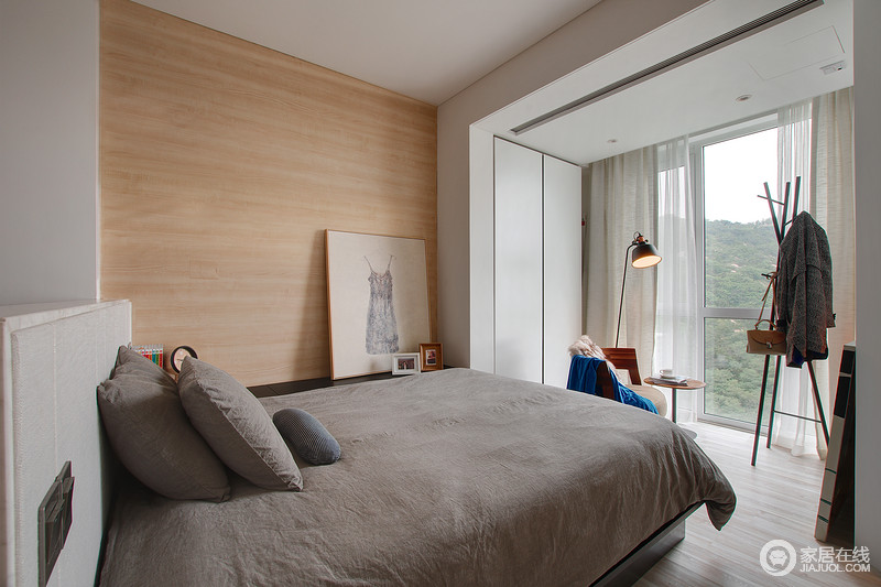 卧室则贴上颇具温馨感的木皮，并利用窗前的纱幔来体现质感；灰色的床品凝结着舒适与简洁，让人生活得安适自在。