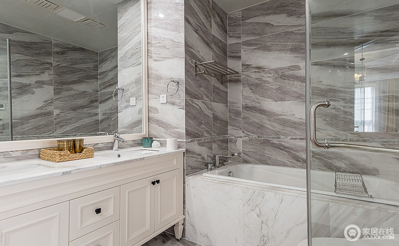 卫生间浅灰色大理石纹理的瓷砖营造一种天然的意境，抽象中具有艺术的生姿；白色的盥洗柜与浴缸为空间带来白色的纯净，整体色彩清淡素雅。