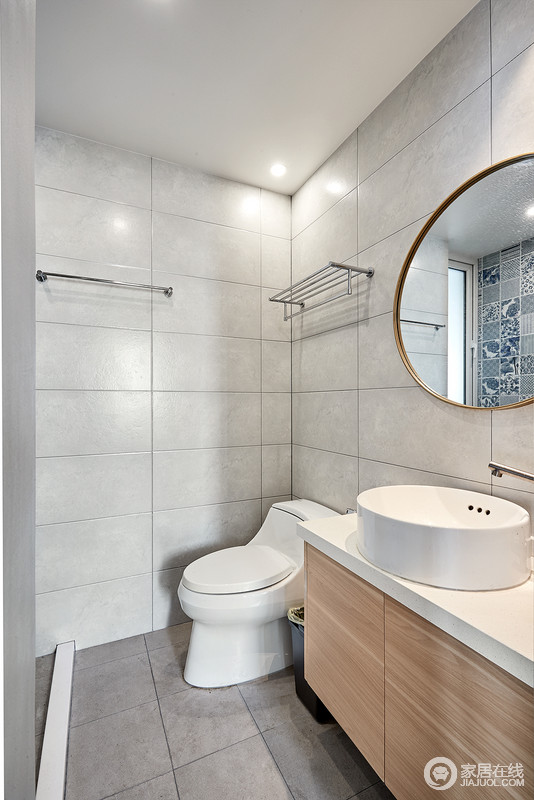 卫生间以灰色瓷砖铺贴墙面，虽然色调显旧却很是干净，实木盥洗柜与金属边框的圆镜搭配出方圆之感，实用而简单。