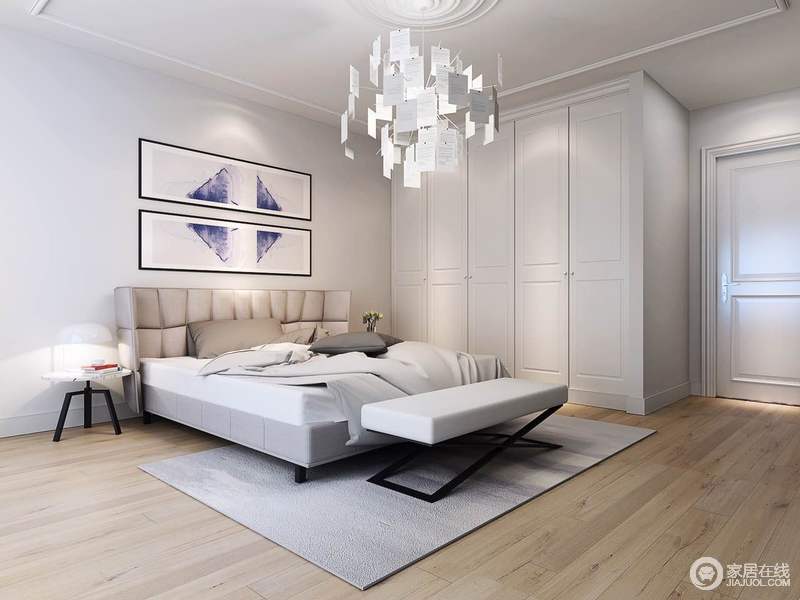 白色的卧室显得大而冷清，铺陈的原木色地板散发出的温和质感，中和了空间冰冷的情绪。墙画与床品色彩的局部营造与造型独特的吊灯，赋予了空间简而空灵的气质。