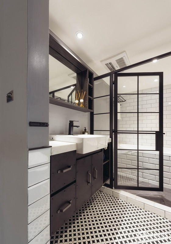 主卧卫浴以黑灰白贯穿，由於设计师考量没有对外开窗，所以选择用白色亮面砖提高卫浴空间的明亮度，而黑色铝合金门解决了干湿的问题，搭配白色关系盆，更为现代利落。