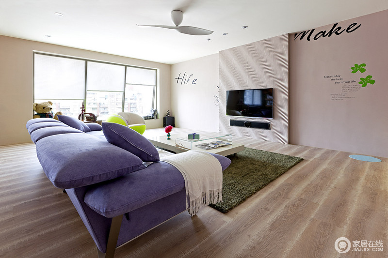 沙发的紫色系成为视觉重点，加上牆面壁贴的巧妙规划，形成随性的居家样貌
