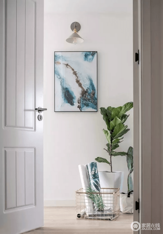 白色调的空间格外简单，推开白色木门，一副蓝色抽象画、一盏灯和盆栽及金属收纳篮便营造了一个小清新的格调，分隔空间的同时，让你随时都被空间的艺术气质所感染。