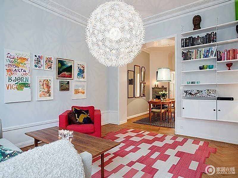 把粉色单人沙发搬进客厅，与粉白拼接的地毯组成甜美，彩色简画挂满墙面，让客厅变得干净纯美，有种小清新的美；墙上书柜放大了空间的实用感，让空间更为饱满生动。