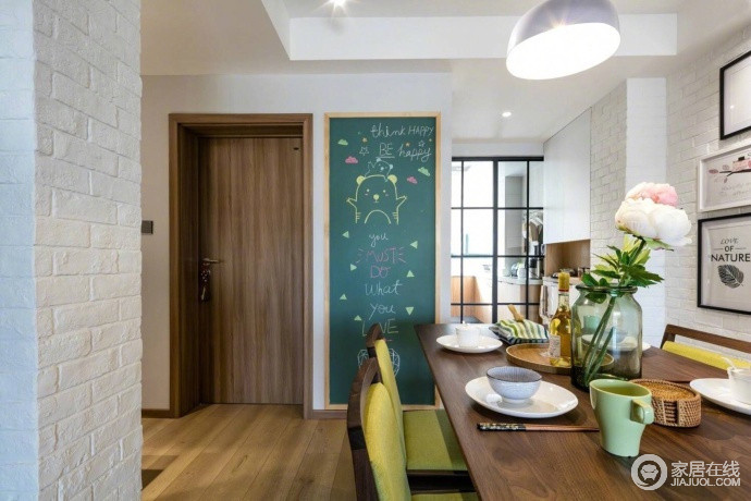 设计师巧妙地将空间进行功能化设计，黑色格栅门将餐厨空间区分，一旁的白色石墙带着原始感，加重了空间的简约；黑白墙和简画装饰着空间，让实木餐桌和绿色餐椅组合出自然清新。