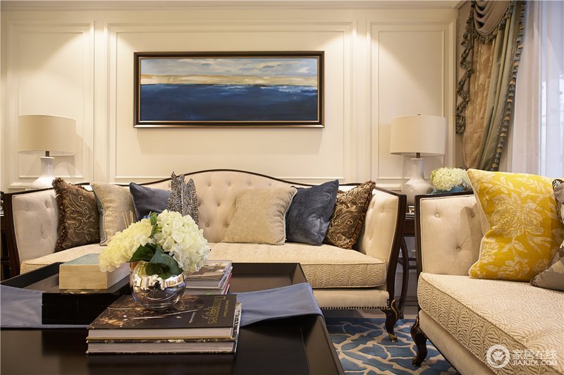 柔和的灯光下，沙发与背景墙色调一致，愈加凸显靠包、装饰画的渲染点缀，让空间的精致感更加典雅细腻。