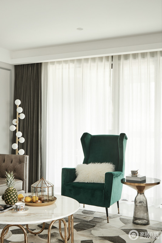 客厅内现代的线条与格局让空间构成一种雅静，浅灰色的石膏墙内敛之中，与深灰色窗帘构成色彩对比，而绿色扶手椅和铆钉沙发的新古典设计，让空间的现代气息变得更为轻奢。