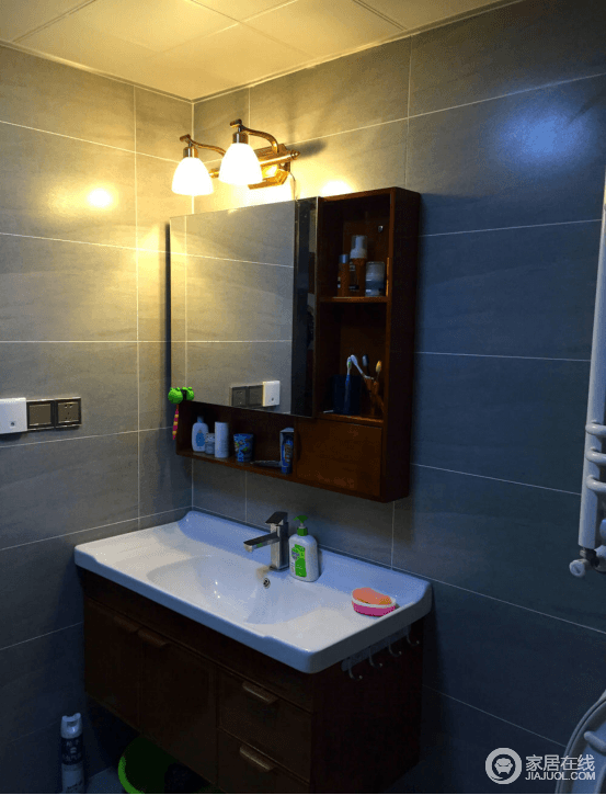 卫生间墙面采用了深灰色的方砖，带着雅致沉静的格调，让卫浴空间多了一丝现代优雅；镜子与收纳盒结合，增加了多功能实用性。