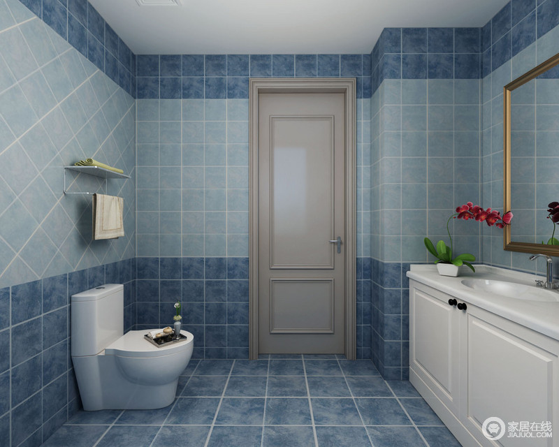 卫生间采用深浅蓝色方砖铺贴，在马桶上方的中央瓷砖则以倾斜方式铺陈，着重凸显背景感。白色盥洗台上放置花卉，清新空气。鎏金框边的浴室镜，平添空间里的一抹低奢质感。