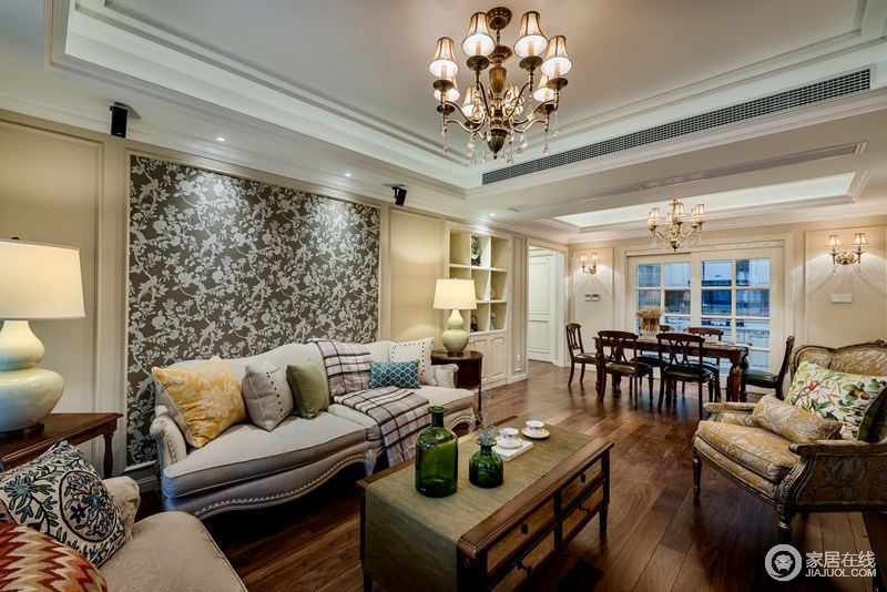 客厅的背景墙以灰底白花为主，意在突出空间的对比，美式沙发因为靠垫和茶几上的瓶器组合，让空间生出色彩来。
