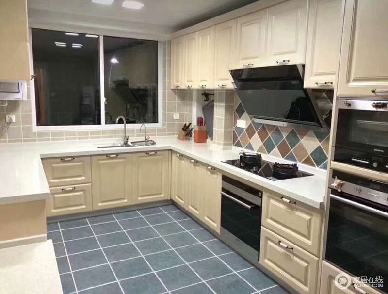 U型设计的厨房充分利用每一寸空间，清新的白色橱柜与马赛克背景墙及灰蓝地板制造出层次，空间简朴整洁；家电被巧妙嵌入柜体，规整又实用。
