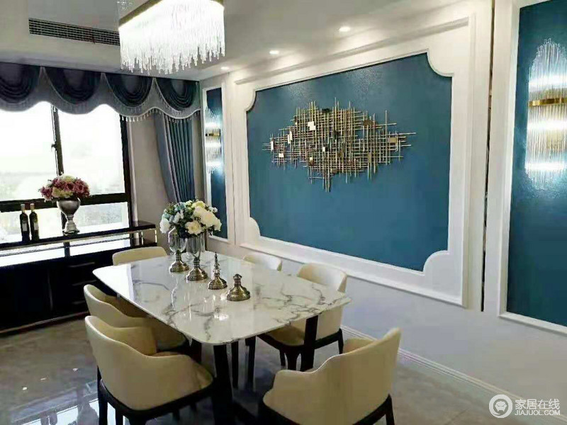 餐厅以白色石膏来强调空间的几何造型，并有蓝色漆来涂刷，让空间多了清雅；金属墙饰搭配水晶灯，增加空间的璀璨，现代餐椅的米色调，打造黑白色调的餐桌，让空间更是现代了不少。