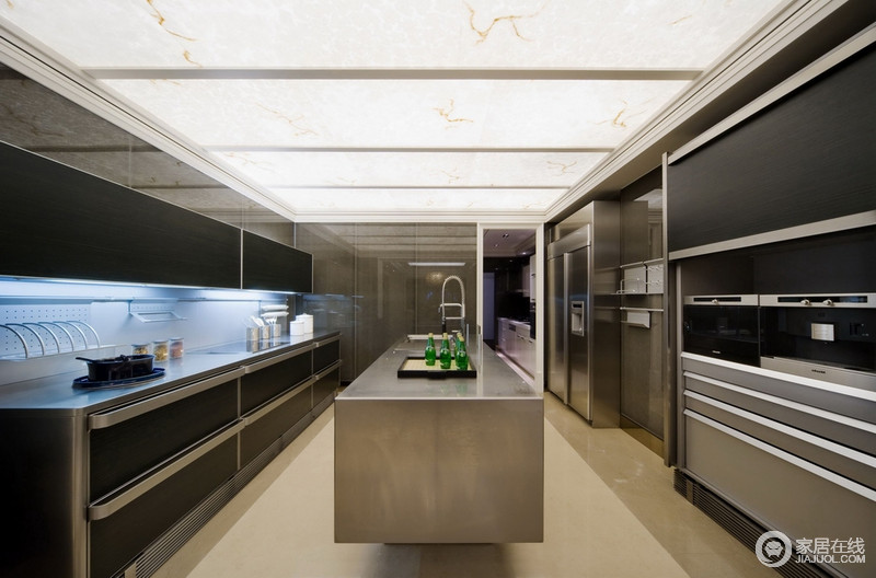 厨房表现出工业质感，透光性的材质装饰天花板带来整个室内的通透性。平面质感良好的黑色橱柜和墙面带着几何的线条感，搭配金属岛台设计，营造出冷色调的未来设计感。