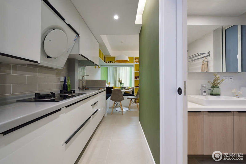 进门以后的走廊改造成了一字型厨房，不占用其他空间单另做一个厨房，橱柜的门板选用了一体的白，这样不会让过道显得压抑；墙面用了灰色的工字砖，使得空间有延伸的感觉，每一寸空间都利用到了极致；厨房对面的墙用了绿色的黑板漆和餐厅区的黄色调更加欢快。