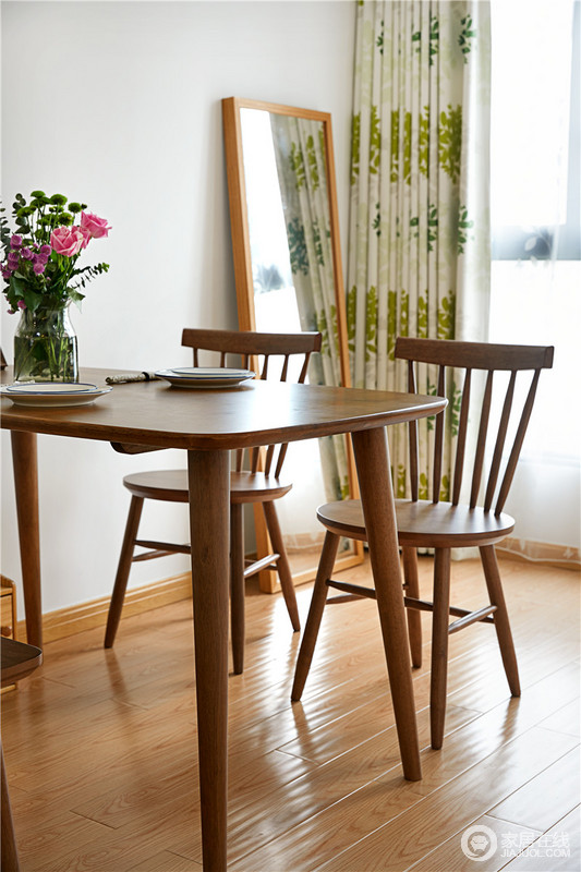 餐厅设计得十分简单，以功能为主，所以实木餐桌餐椅便是主角，它成为一家人互动的纽带；餐桌摆上两套餐具和花卉，与绿叶窗帘搭配出自然小清新。