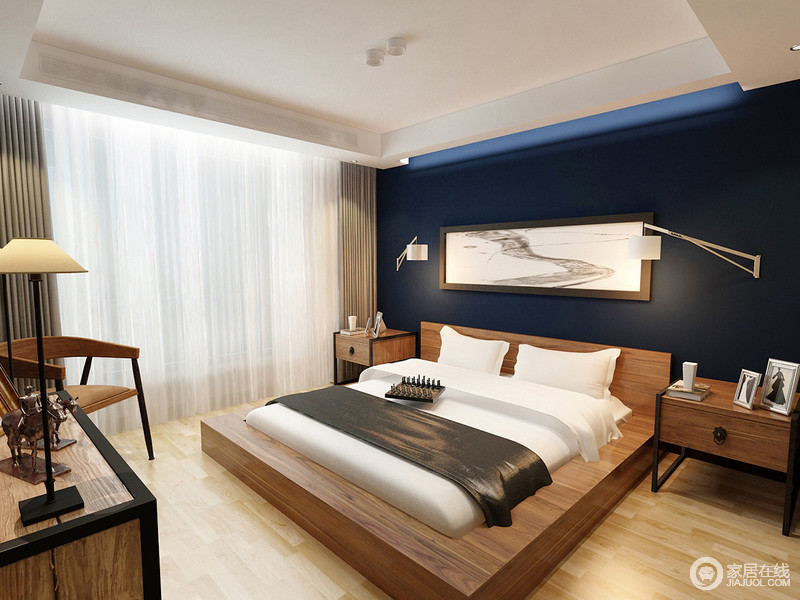 卧室氛围极具视觉感，背景墙上墨蓝像一汪深邃的大海，装饰的黑白画对比鲜明。原木家具打破背景的冷色调，温暖了空间氛围；宽大的床板上，白色床垫简洁利索，混搭着灰褐床旗。