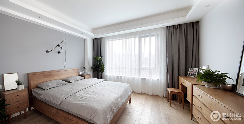 卧室以浅灰色漆粉刷墙面，实木家具的温实朴质给予空间一种暖调；而深灰色窗帘与浅灰色床品构成色彩对比，白色纱幔营造朦胧意境，渲染出一种轻盈感。