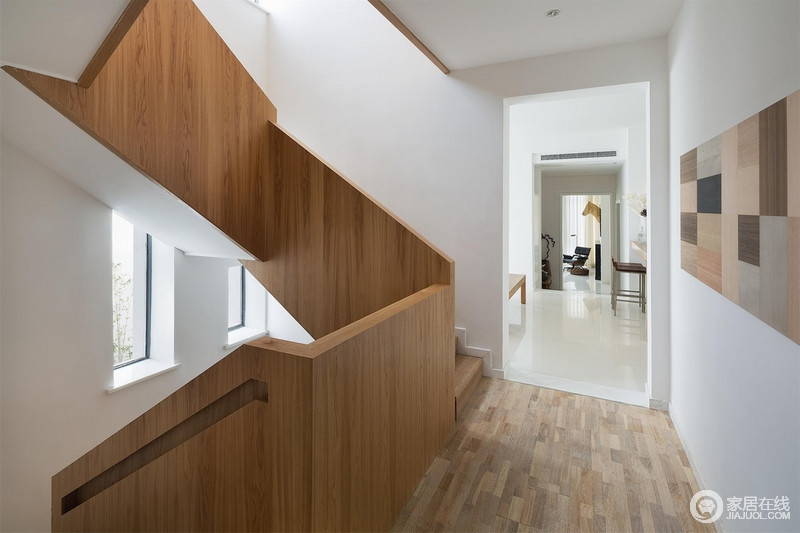 走廊中通体白色寂静利落，木材装裱的楼梯也安顺自然。