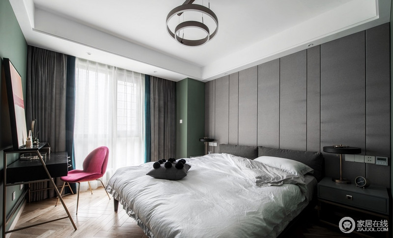 卧室以白色和灰色为主调，深色的恰当利用，背景墙灰色板材设计提升了家里整体的艺术气质，更为稳重；承重墙以绿色着墨，搭配粉色单椅、蓝灰色窗帘，缔造温馨。
