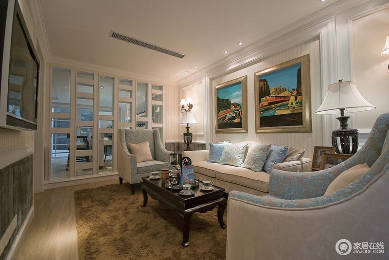 柔浅的蓝色与白色穿插而成的布艺沙发勾勒出绒软的效果，精巧的木质茶几古朴，却因两幅色彩亮丽、夸张的画作让空间散发些些许另类的古典美。
