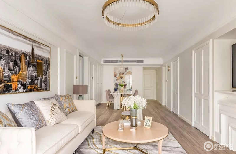 客厅整体以米白色为主，搭配富有层次的木线条，并辅以精致软装点缀，地面木色和墙面白色形成鲜明的对比，空间更加具有层次感。