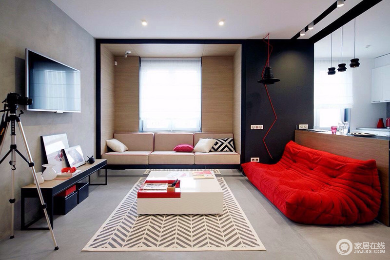 客厅水泥墙和地面构成灰色冷调，与几何结构沙发区的庄正截然不同，却颇有趣意；红色布艺沙发的柔软与色彩上的热烈，和素色几何地毯衬托着黑白家具，愈显时髦。