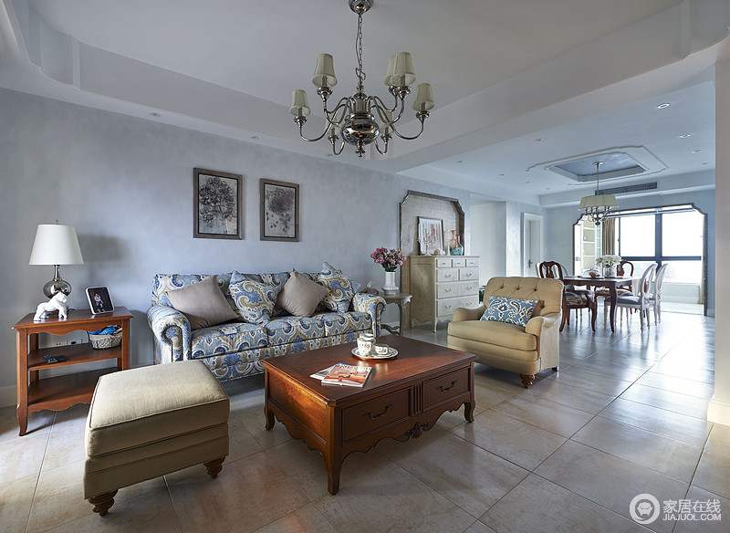 客厅里深灰蓝墙面打底，营造出清新爽质的氛围。摩洛哥图案的沙发作为空间点睛焦点，与米黄沙发椅、凳和褐红色茶几、边几强烈的对比，使略显空洞的空间多了份旖旎。